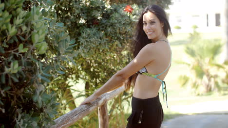 dama en ropa de playa sosteniendo una barandilla de madera