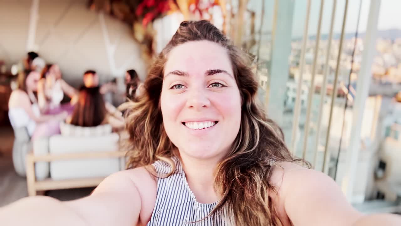 Vlogger donna felice che sorride in un rooftop bar di Atene.