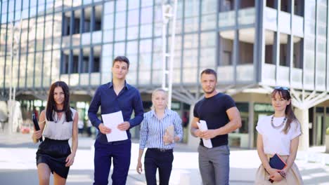 portrait of an attractive multi-racial business team, as they walk outside office building modern glass fronted office building towards the camera. business people meeting outside