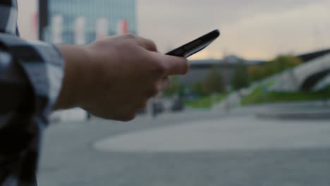 Handheld-view-of-man-who-using-mobile-phone-in-town