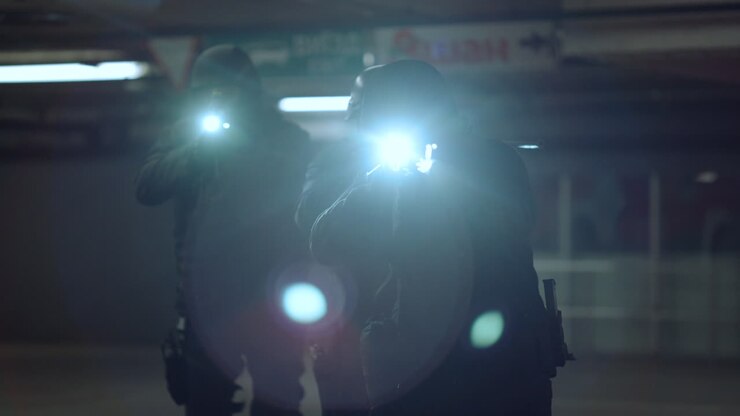 Team bewaffneter SWAT-Beamter schießt aus Scharfschützengewehren mit Taschenlampen.