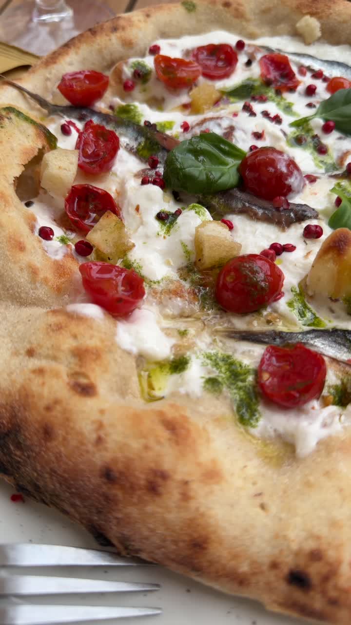 Primo piano di pizza gourmet con burrata, acciughe e basilico