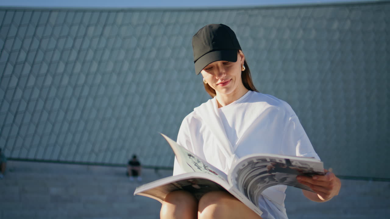 Calm lady looking magazine at sunny street closeup. Happy woman reading outdoors