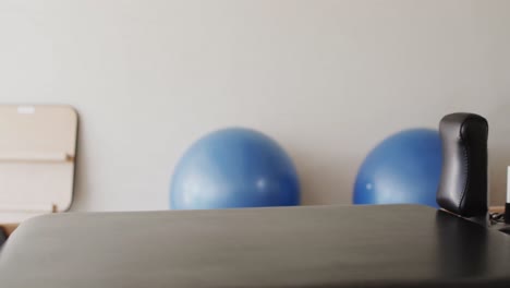 close up of empty pilates rehabilitation room with reformer and exercise balls, slow motion