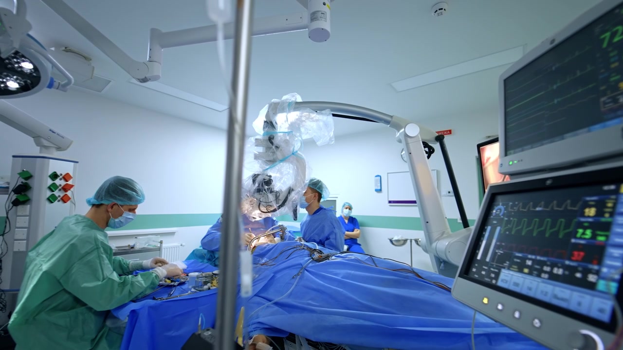 Operazione neurochirurgica eseguita in una moderna sala operatoria con diverse attrezzature. I medici usano il microscopio durante l'intervento