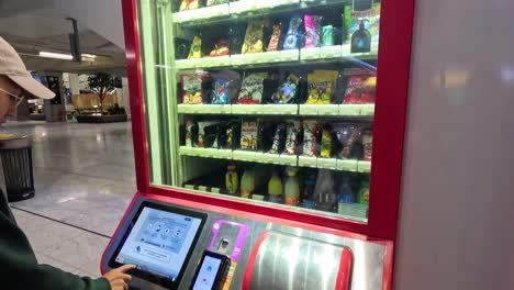 man interacts with a digital vending machine in mall