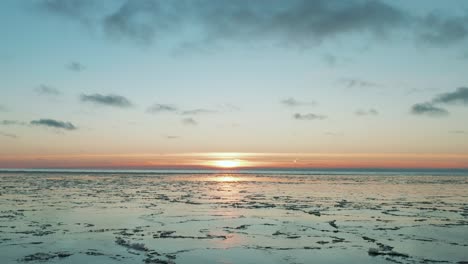 drone volando sobre el mar en calma con hielo derretido en la superficie al atardecer, amanecer