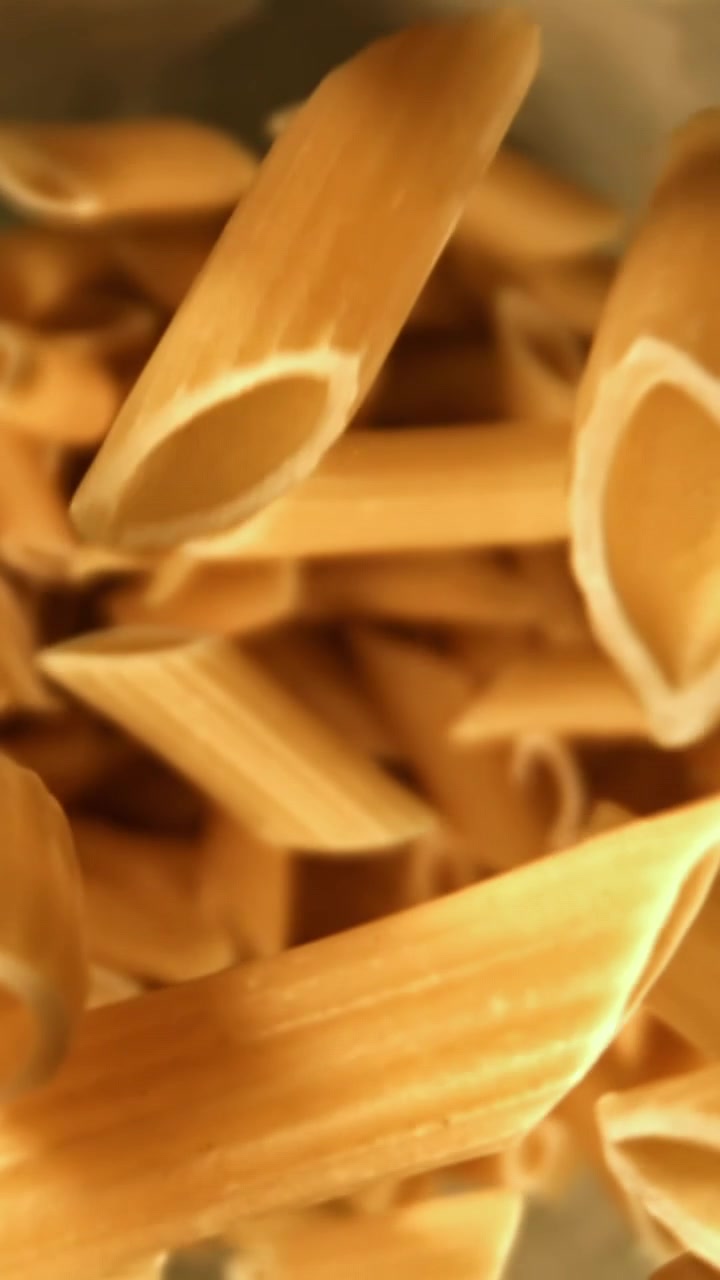 Primo piano di penne crude che cadono al rallentatore