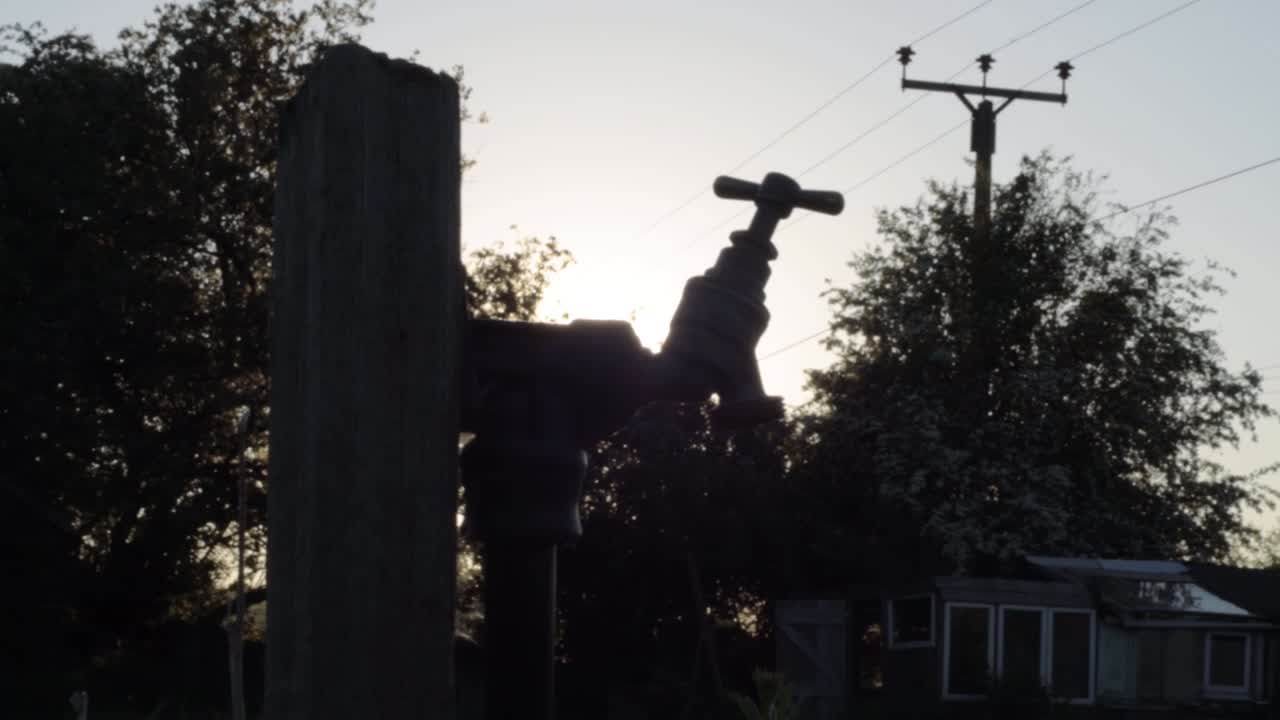 Faucet tap in garden wide silhouette close panning shot