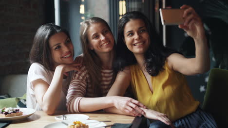 happy friends taking a selfie in a cafe