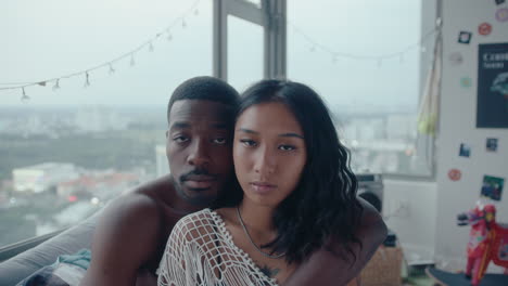 young romantic couple cuddling and looking at camera in bedroom