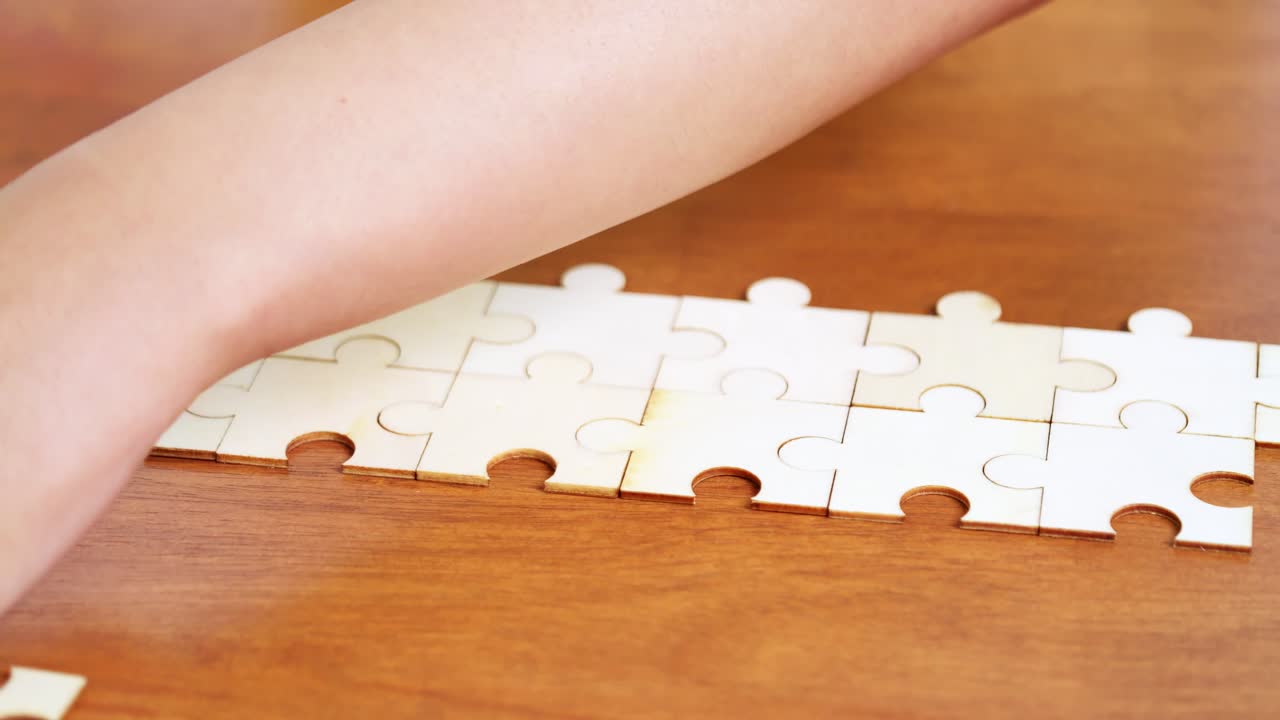A hand delicately places a puzzle piece showcasing focus and problem-solving a cozy environment