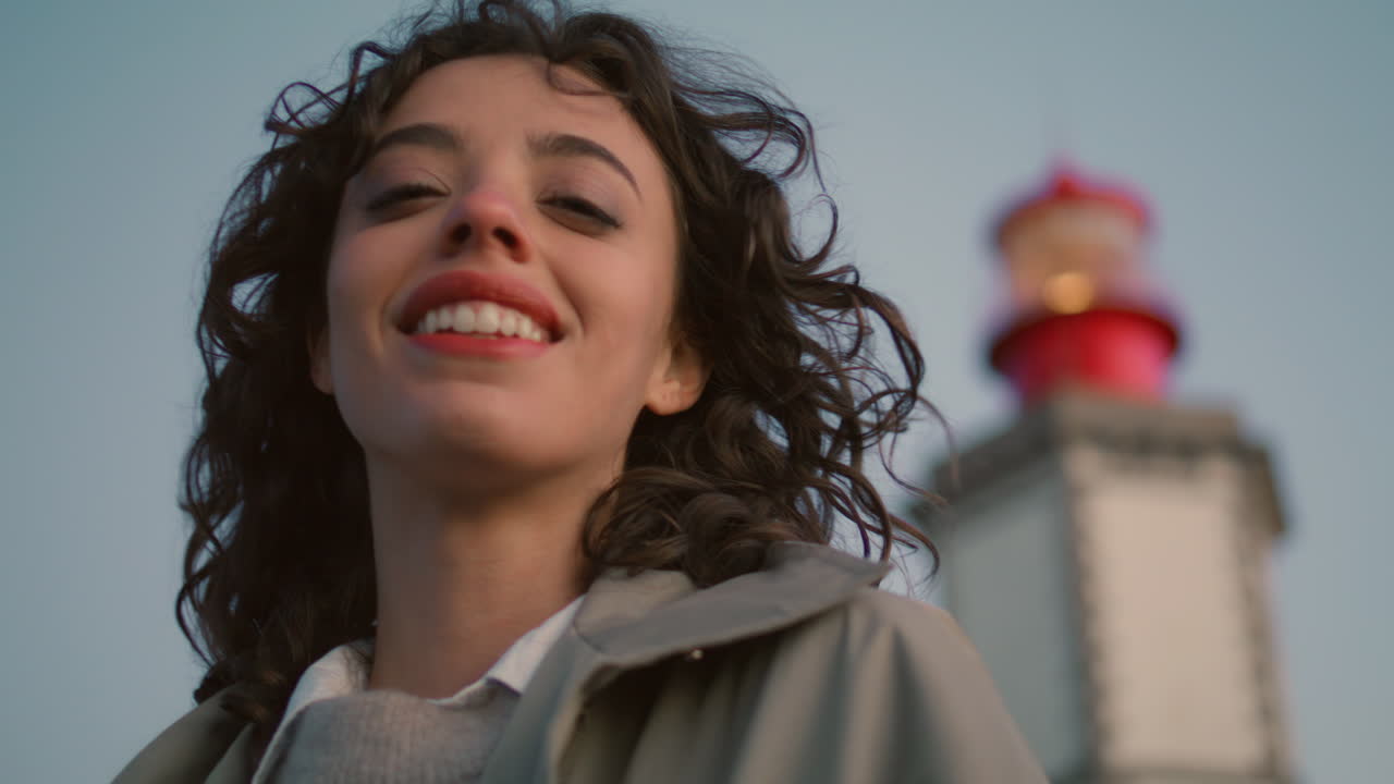 Closeup travel girl looking camera at evening lighthouse view. Happy woman dream