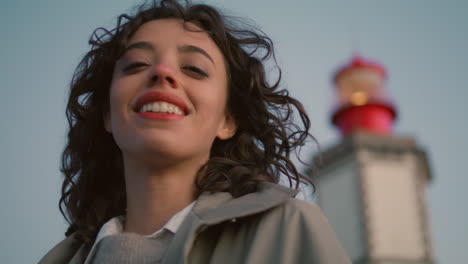 mujer de viaje de primer plano mirando la cámara en la vista del faro de la noche. sueño de mujer feliz
