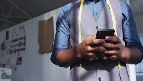 Mixed-race-man-using-smartphone-in-creative-office