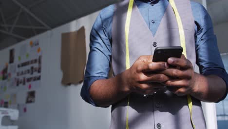 hombre de raza mixta usando un teléfono inteligente en la oficina creativa