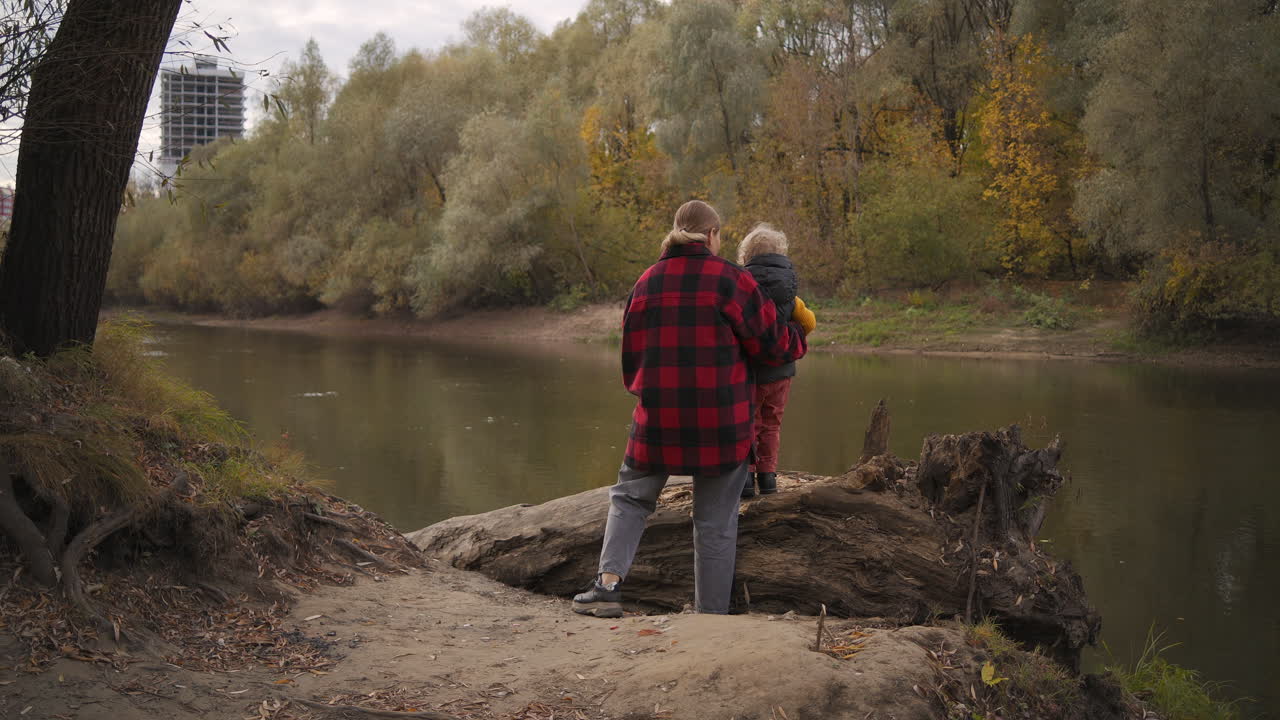 행복한 어머니는 가을의 날 숲에서 아기와 함께 휴식을 취하고 있으며, 어린아이를 돌보는 것과 엄마의 사랑을 소통하고 있습니다.