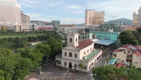 drone orbit shot of church in taipa village with casinos in background