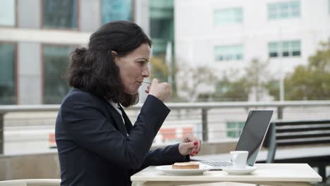 Geschäftsfrau-Benutzt-Laptop-Und-Isst-Dessert-Im-Café