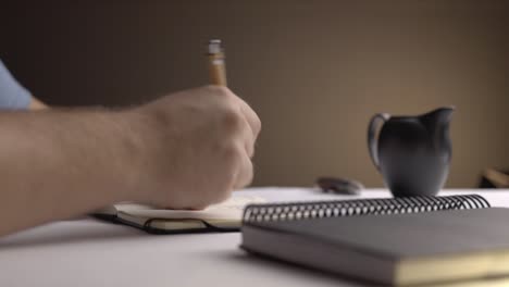 static shot of a man writing something in a small notebook moody setting