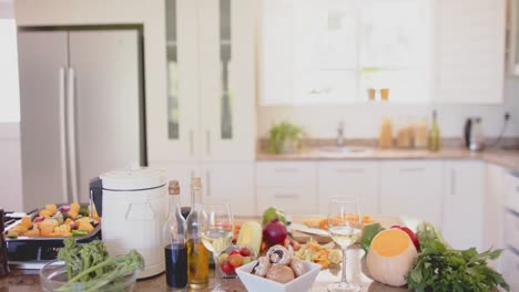 vegetables and glasses of white wine on countertop in kitchen