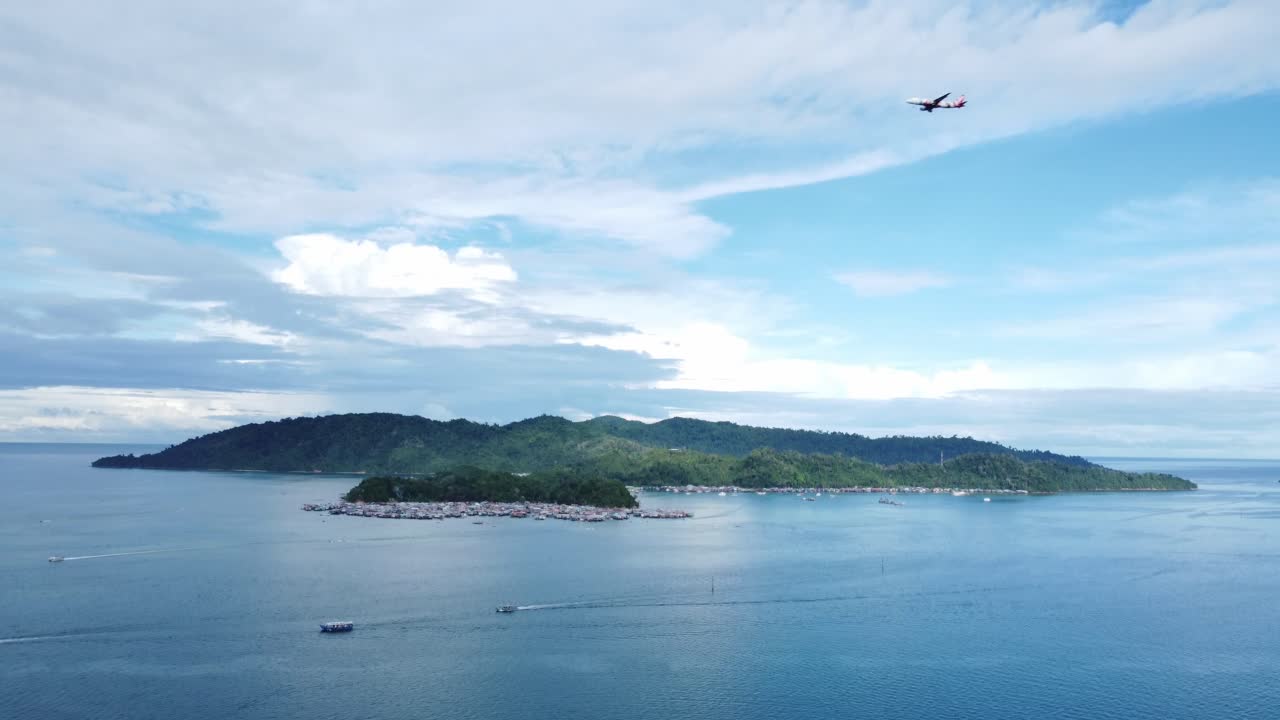 드론이 배와 바다 물 위를 날아다니며 지평선 너머의 섬을 바라보며 아오르며 날아가며 카메라를 지나갑니다. 말레이시아 코타키나발루의 늦은 아침.