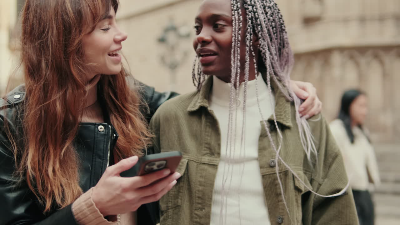 Two Young Women Friends Laughing and Looking at Smartphone