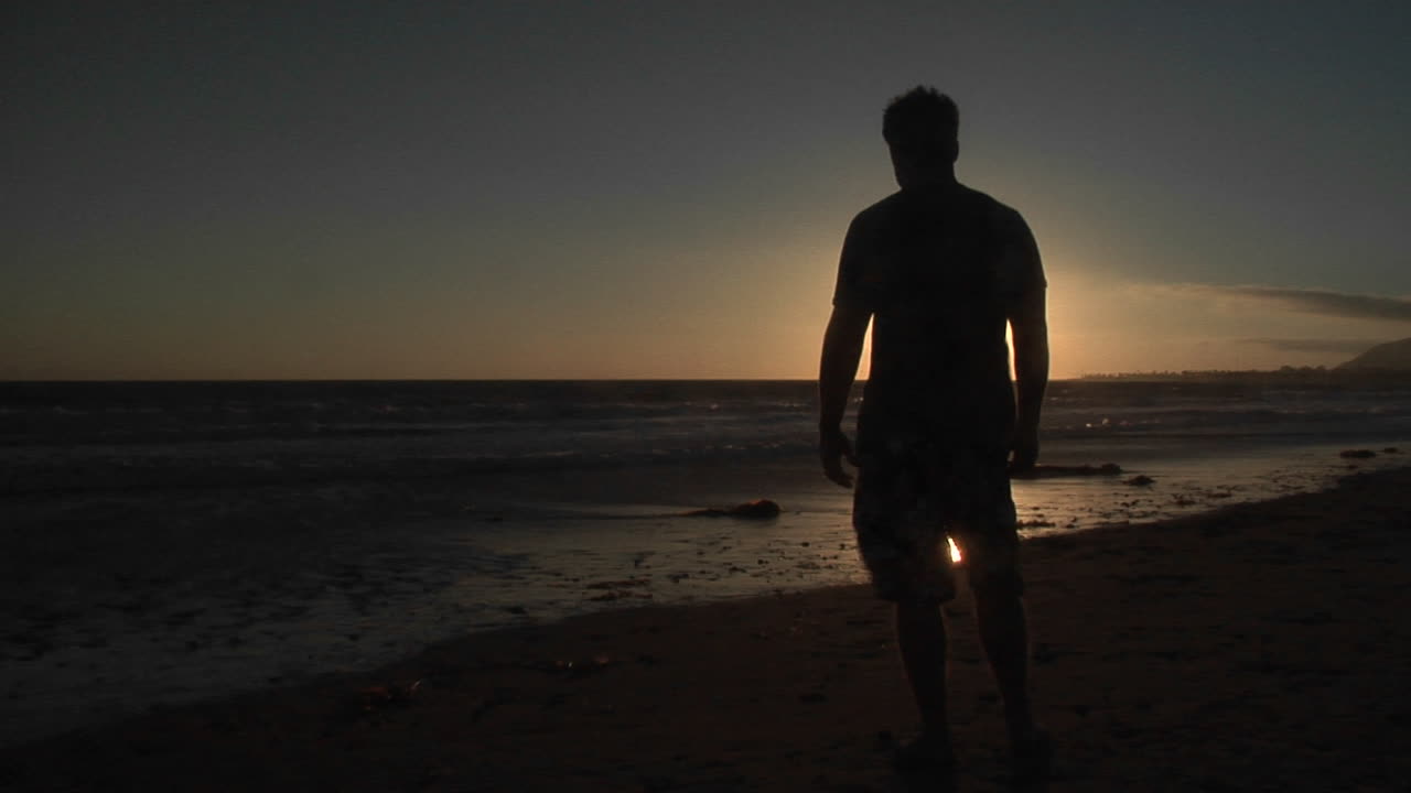 Un uomo sta in piedi da solo su una spiaggia ventosa