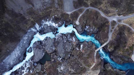 stunning wild blue river and waterfall barnafoss in volcanic landscape, aerial top down panorama