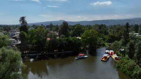 aerial view of trajinera boats moving on the xochimilco lake, in sunny mexico