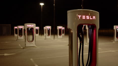 deserted tesla supercharger charging stations at night, tilt up shot
