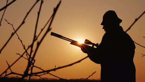 Silhouette-Eines-Jägers-Mit-Einer-Waffe,-Die-Sonnenstrahlen-Leuchten-In-Seinem-Gesicht