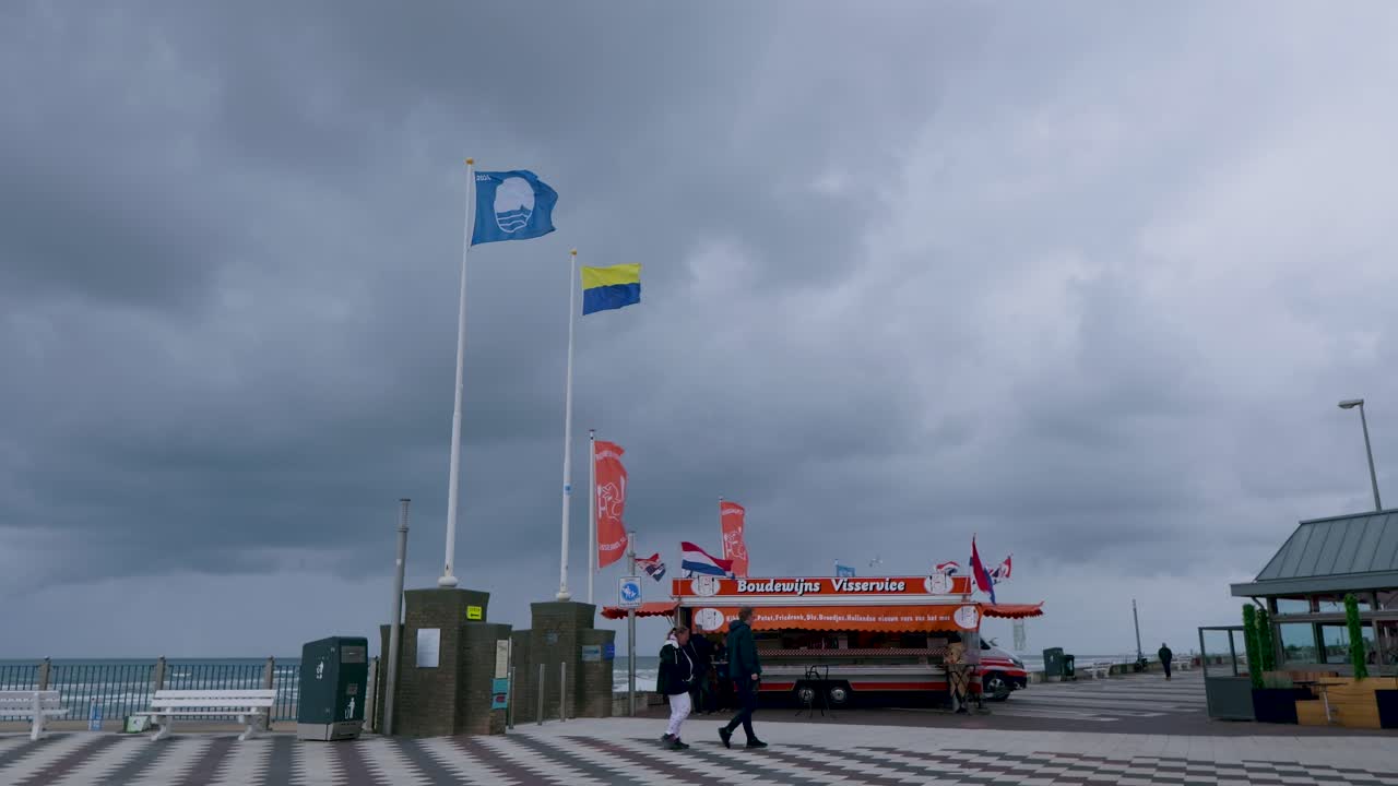 Beach Pier Scene with Food Stalls and Flags on a Cloudy Day