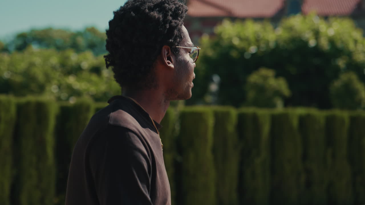 Young Black Man Walking and Looking Around in a Sunny Park