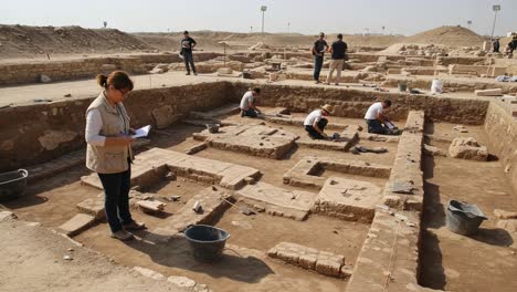 archaeologists engaged in excavation work at a historical site, carefully analyzing artifacts and unearthing remnants of ancient structures during a clear day