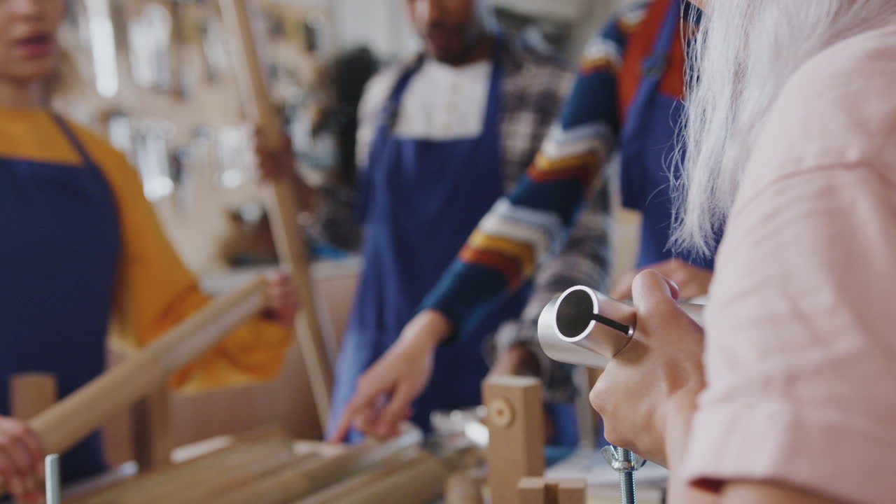 Close Up Of Multi-Cultural Team In Workshop Assembling Hand Built Sustainable Bamboo Bicycle Frame