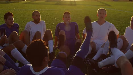 un equipo de fútbol sentado en un círculo jugando un juego divertido al atardecer