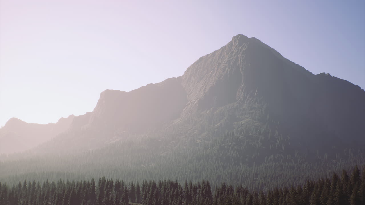 Majestic mountain peak rises above lush forest in early morning light