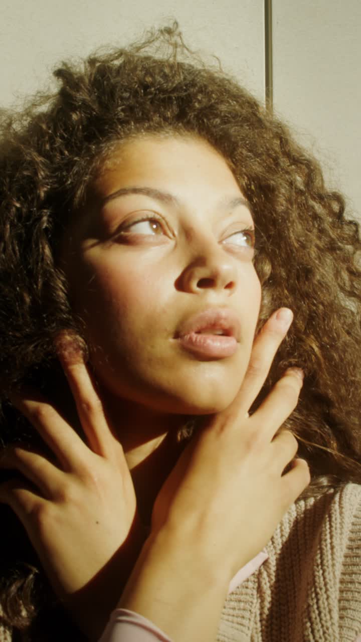 Woman with curly hair posing in sunlight