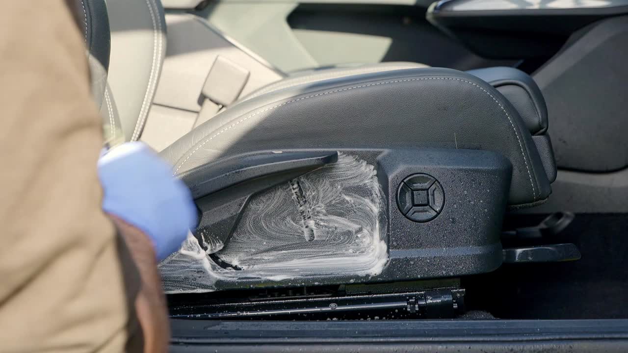 Cleaning interior plastic on car seat with cleaner and a brush