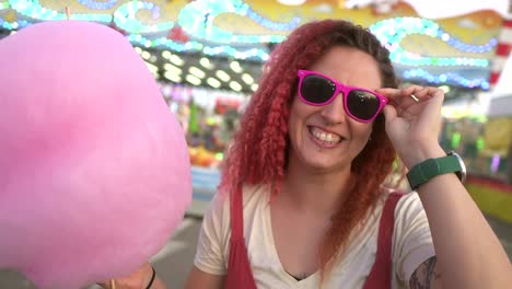 happy woman with cotton candy puts on sunglasses and dances at the fair