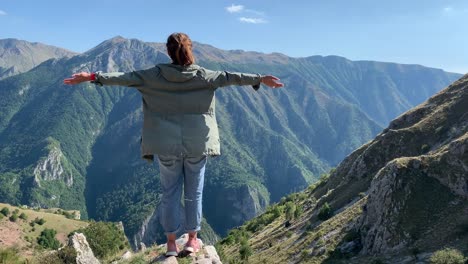 girl standing on the edge of the cliff high in mountains