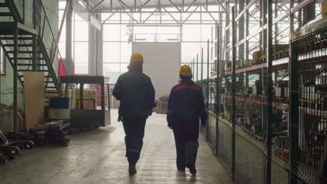 two workers walking in factory warehouse