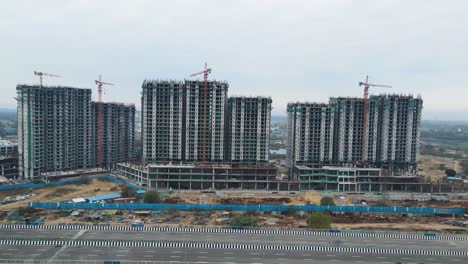 aerial drone shot displaying a bird’s-eye view of multiple under-construction buildings near dwarka expressway, highlighting rapid urban development.