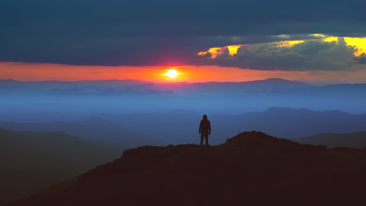 el hombre de pie en la cima de la montaña contra un pintoresco amanecer.