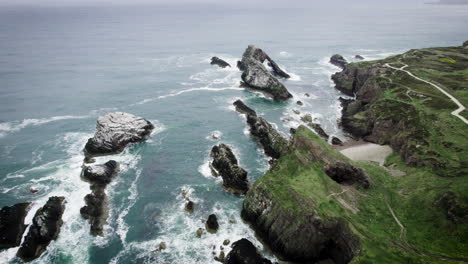 Aerial-shot-by-drone-of-ocean-blue-waves-break-on-high-cliff-of-a-rocky-mountain