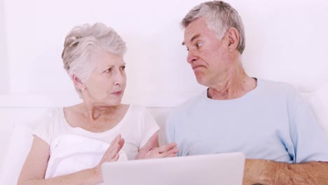 una pareja de mayores en la cama hablando.