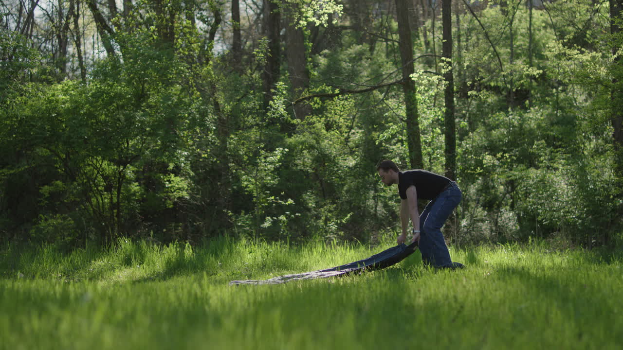 Man laying tarp in grassy field