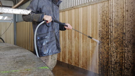 high power jet washer cleaning grime of farm barn wall