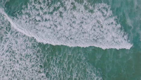 vista de arriba hacia abajo de las olas espumosas en la playa tropical de razo en carballo, españa